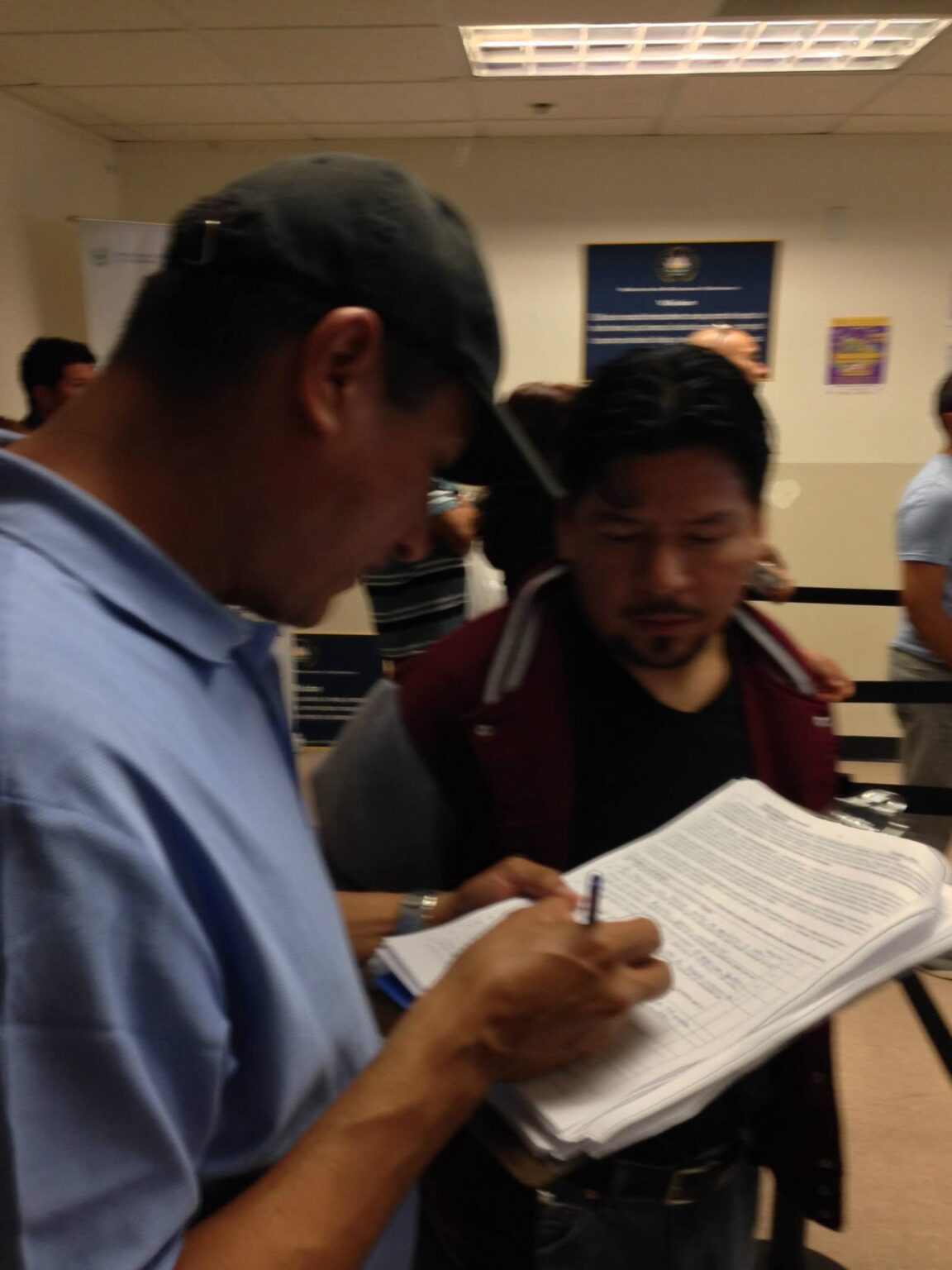 Analitika interviewer filling in a paper questionnaire while a respondent looks on