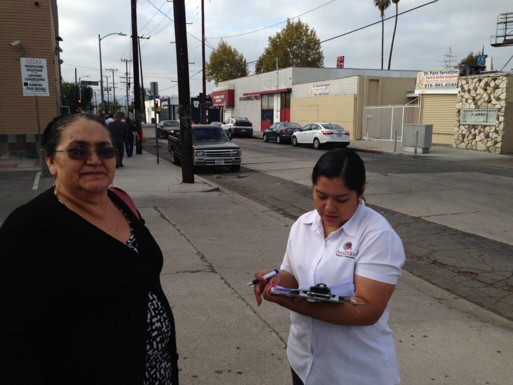 Analitika interviewer taking notes while talking with a woman on a Los Angeles sidewalk