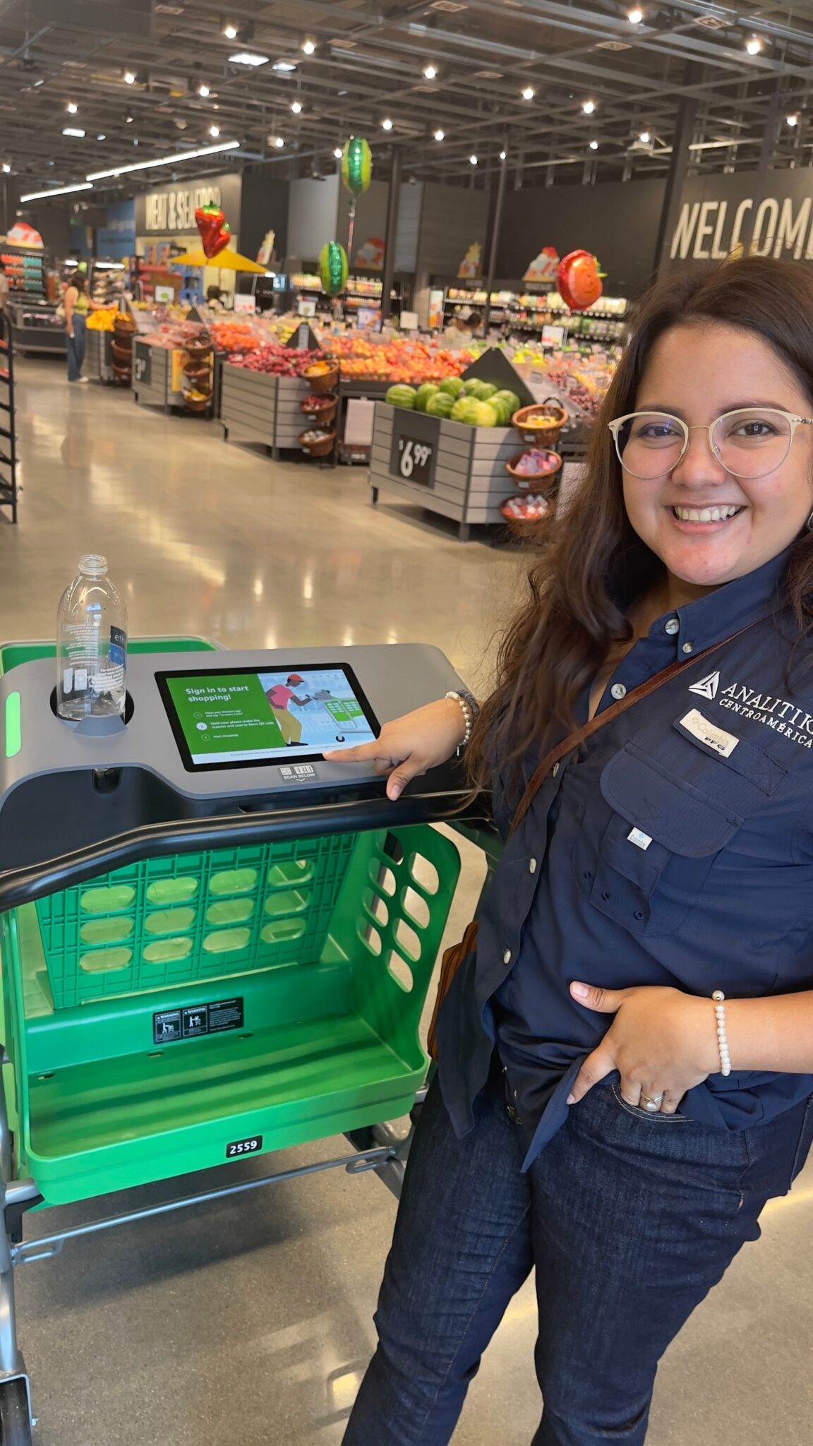 Analitika team member smiling next to a smart shopping cart in a grocery store in Cerritos, California