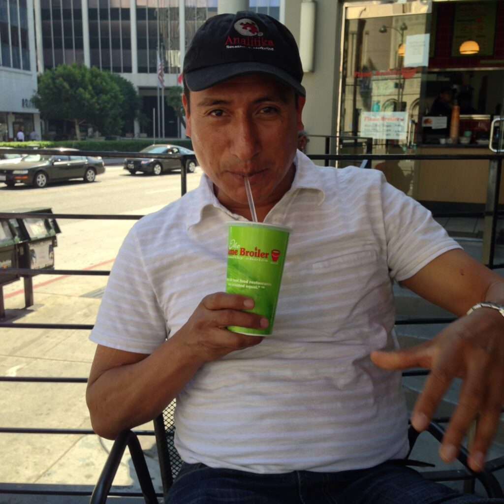 Analitika interviewer in a company cap having a drink on a restaurant patio during a lunch break in Los Angeles