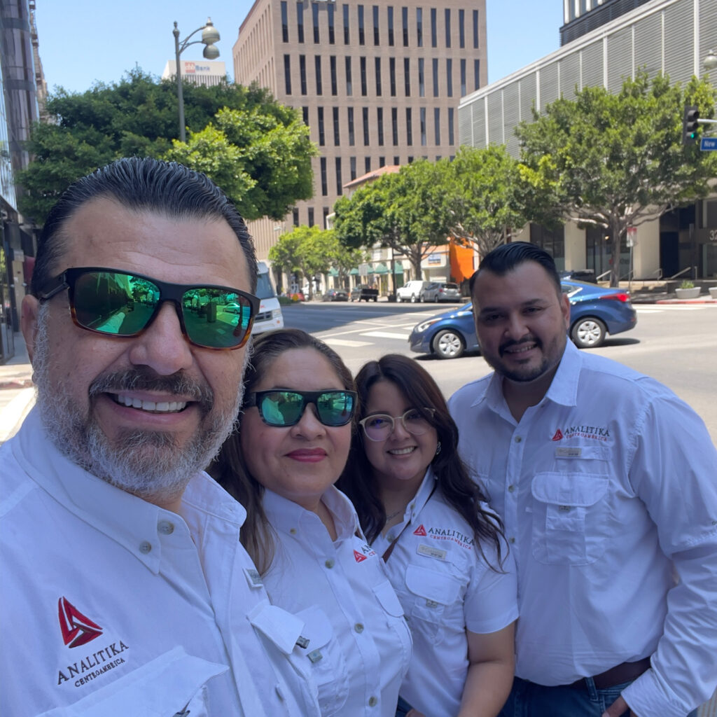 Four Analitika team members in white company shirts taking a selfie on a street in Koreatown, Los Angeles