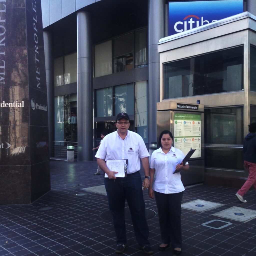 Two Analitika field interviewers with clipboards next to the Wilshire/Normandie Metro station entrance in Los Angeles