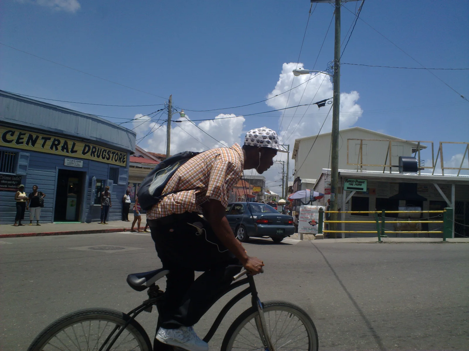 Calle comercial de Belize City con un ciclista frente a una farmacia