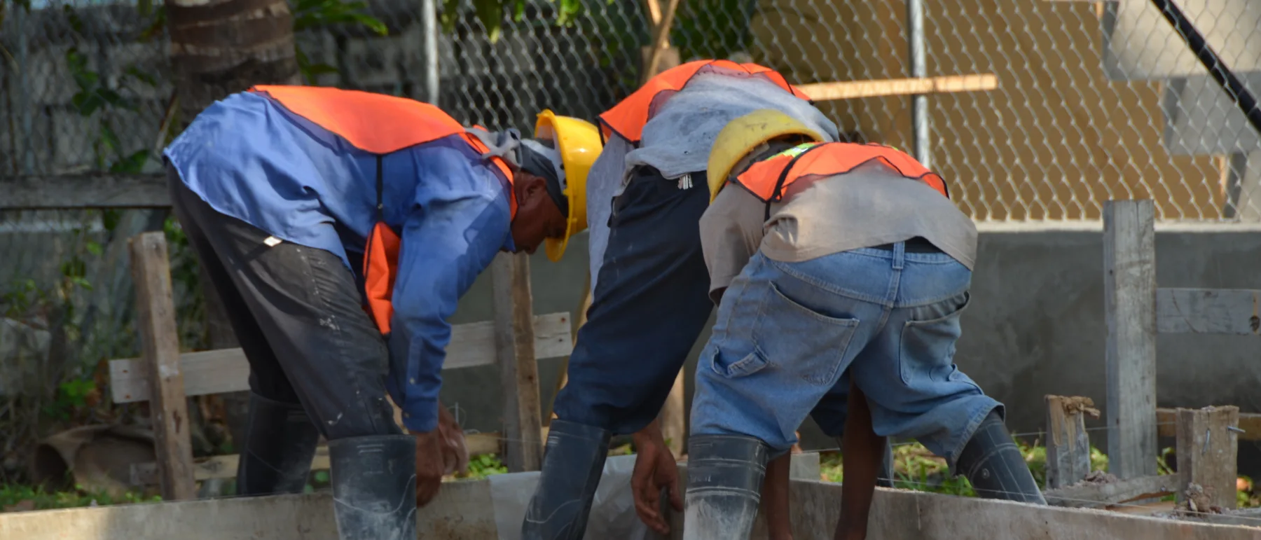 Contratistas beliceños nivelan una losa de concreto en una obra