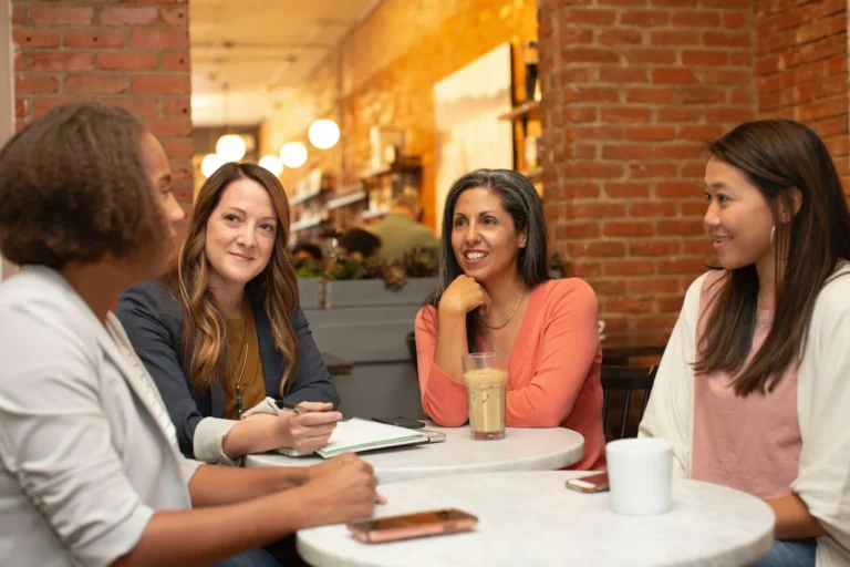 Cuatro mujeres conversan alrededor de una mesa