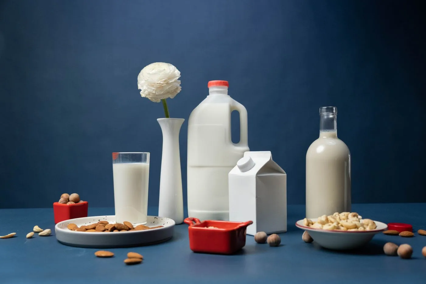Vaso, jarra, botella y envase de leche sobre una mesa azul