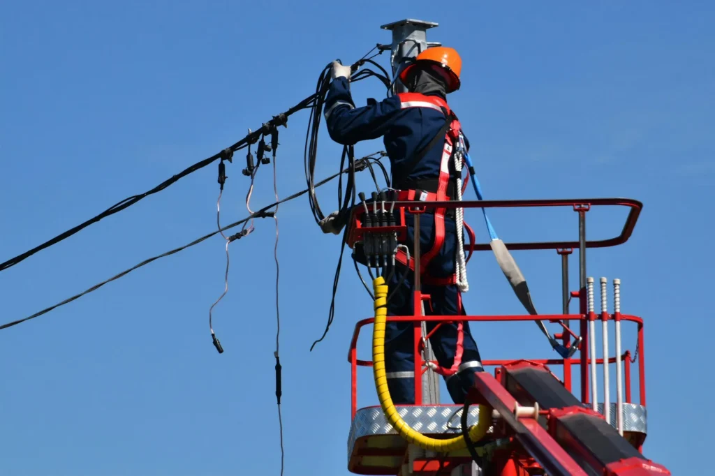 Técnico con casco y arnés repara líneas eléctricas aéreas