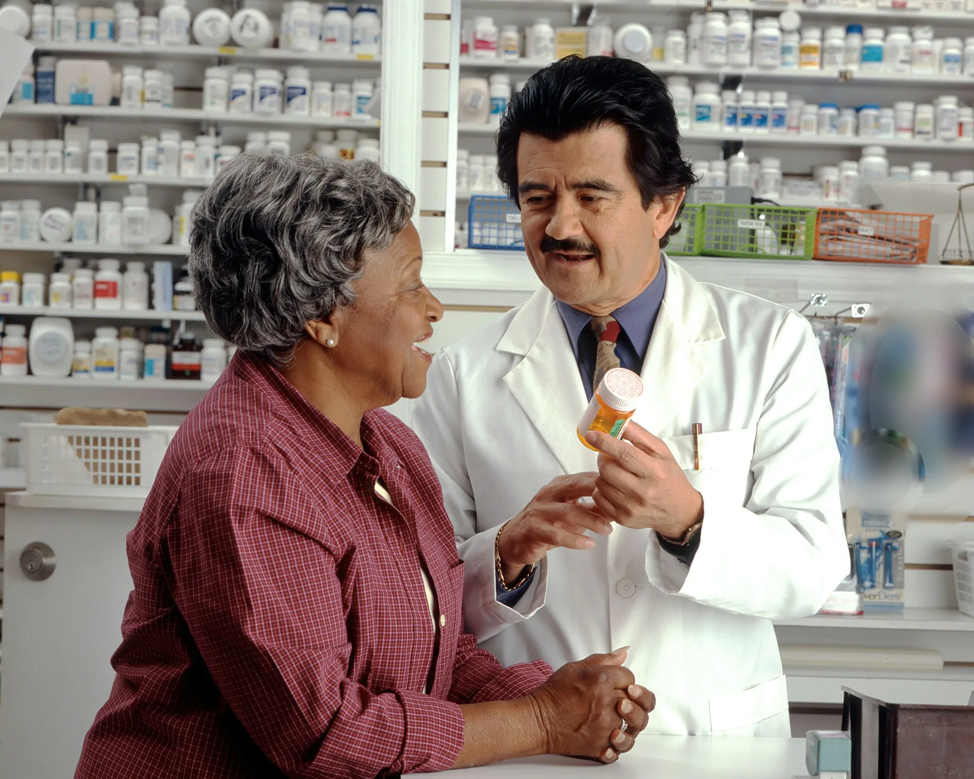 Farmacéutico explica un medicamento a una paciente en el mostrador