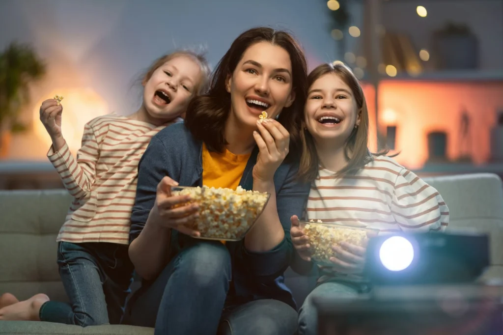 Una madre y sus hijas comen palomitas mientras ven una película en casa
