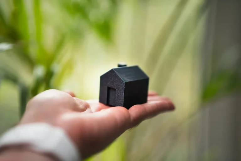 Mano sostiene una casa en miniatura